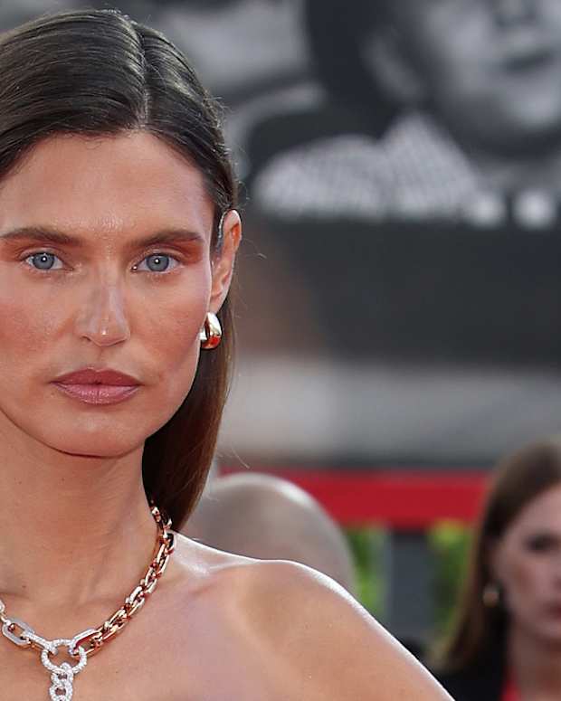 Bianca Balti poses in a gold chainlink necklace and sports a slicked back down-do.